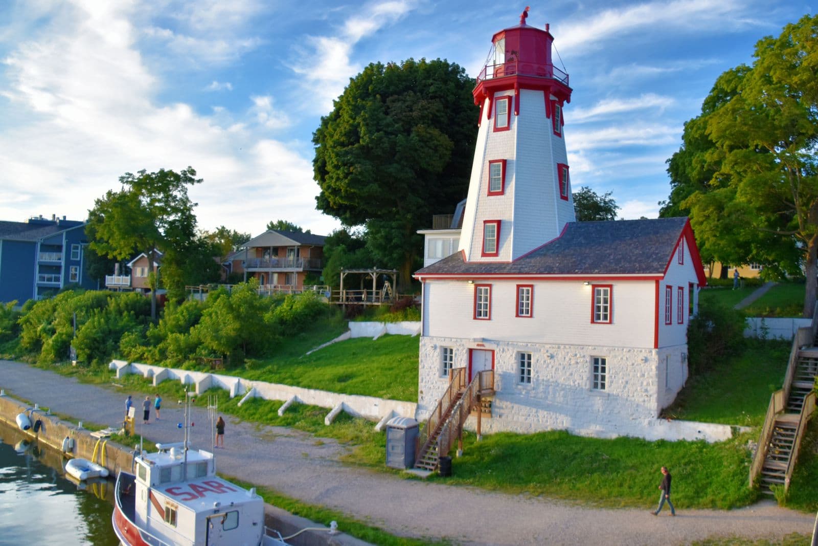 A white lighthouse on a rocky Lake Huron shoreline under a clear sky