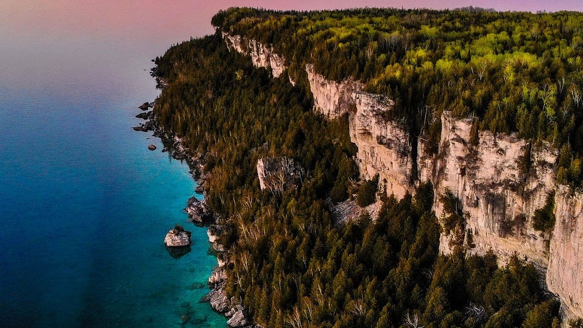 Aerial view of rugged Ontario shoreline cliffs meeting the water at sunset